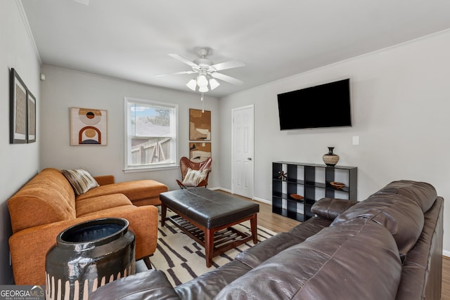 living area featuring a ceiling fan, crown molding, baseboards, and wood finished floors