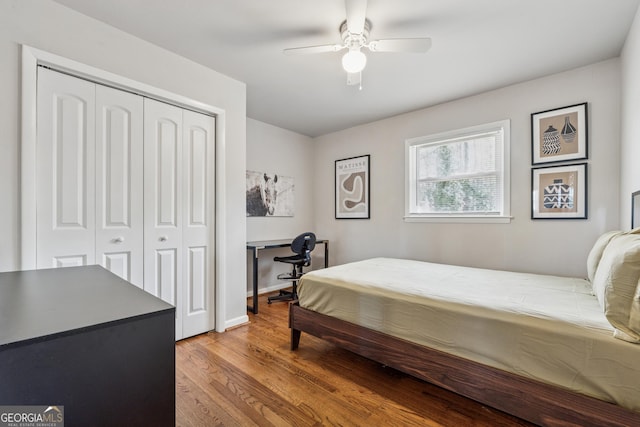 bedroom featuring a closet, baseboards, wood finished floors, and a ceiling fan