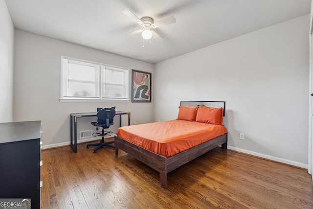 bedroom featuring hardwood / wood-style floors, visible vents, baseboards, and ceiling fan