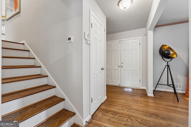 entryway with visible vents, baseboards, wood finished floors, and stairs