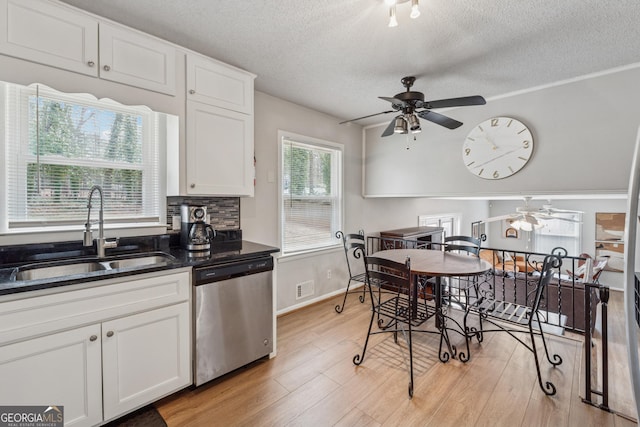 kitchen featuring light wood-style flooring, a sink, white cabinets, stainless steel dishwasher, and tasteful backsplash