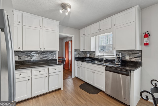 kitchen with a sink, stainless steel appliances, white cabinetry, and light wood finished floors