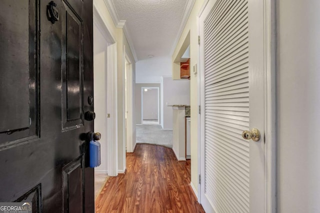 corridor with baseboards, a textured ceiling, and wood finished floors