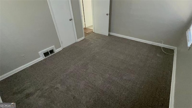 unfurnished bedroom featuring dark carpet, visible vents, and baseboards