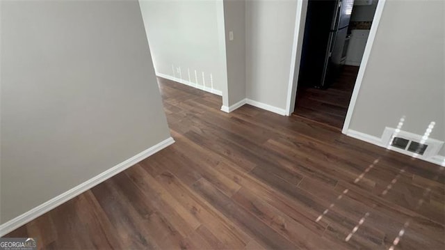 unfurnished room with dark wood-style floors, visible vents, and baseboards