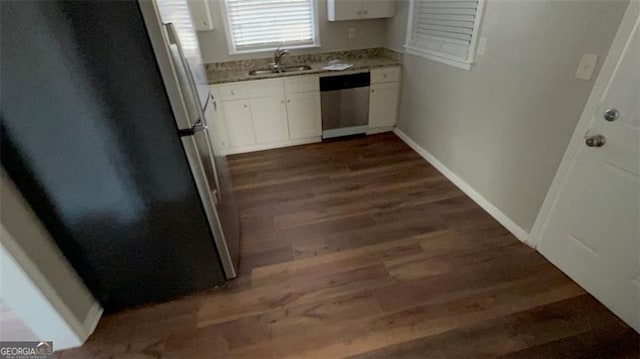 kitchen featuring dark wood finished floors, appliances with stainless steel finishes, white cabinetry, a sink, and baseboards