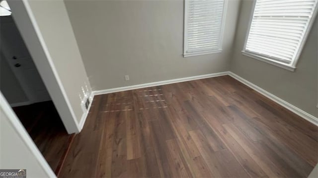 empty room with dark wood finished floors and baseboards