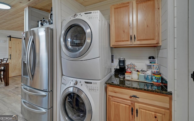 laundry room with laundry area, wood walls, stacked washer and clothes dryer, and light wood-style floors