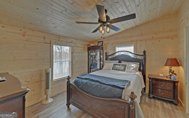 bedroom featuring wooden walls, lofted ceiling, wood ceiling, ceiling fan, and wood finished floors