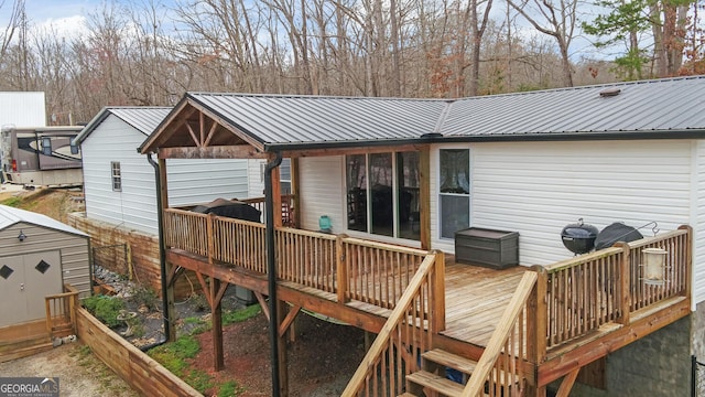 back of property featuring metal roof, a storage unit, an outdoor structure, and a wooden deck