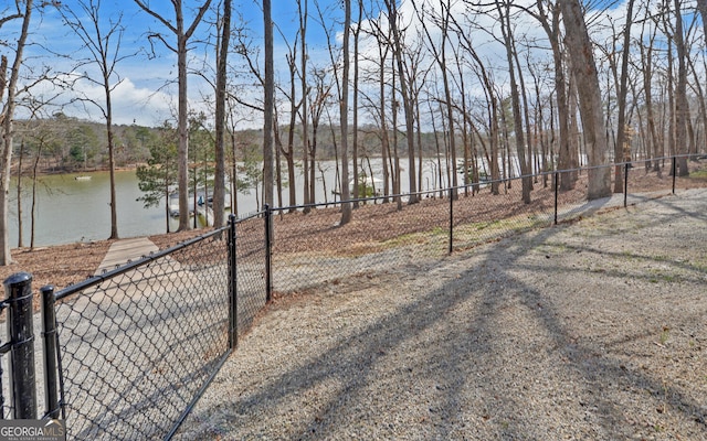 view of yard with a boat dock, a water view, and fence