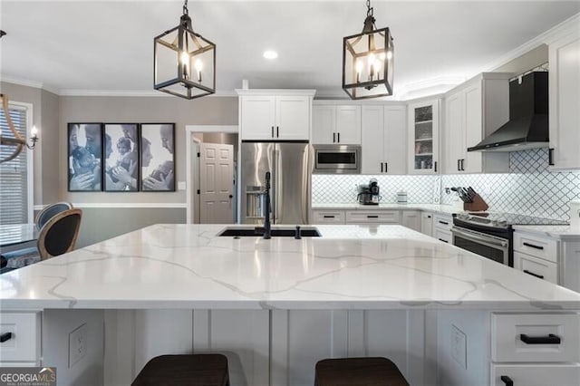 kitchen with stainless steel appliances, backsplash, ornamental molding, white cabinets, and wall chimney exhaust hood