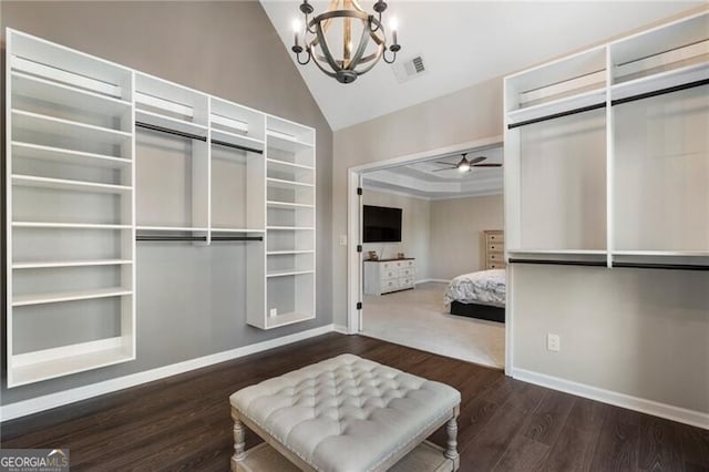 spacious closet with lofted ceiling, ceiling fan with notable chandelier, wood finished floors, and visible vents