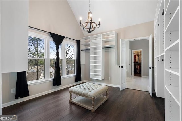 walk in closet with high vaulted ceiling, a chandelier, and dark wood-type flooring