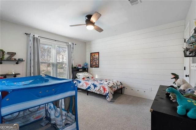 bedroom featuring ceiling fan, wood walls, carpet, and visible vents