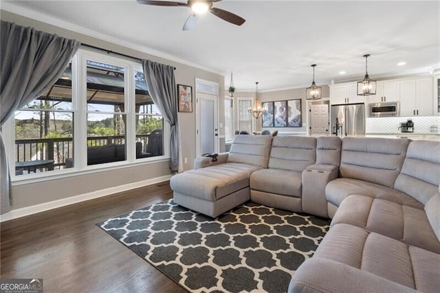 living area featuring crown molding, recessed lighting, dark wood-type flooring, baseboards, and ceiling fan with notable chandelier