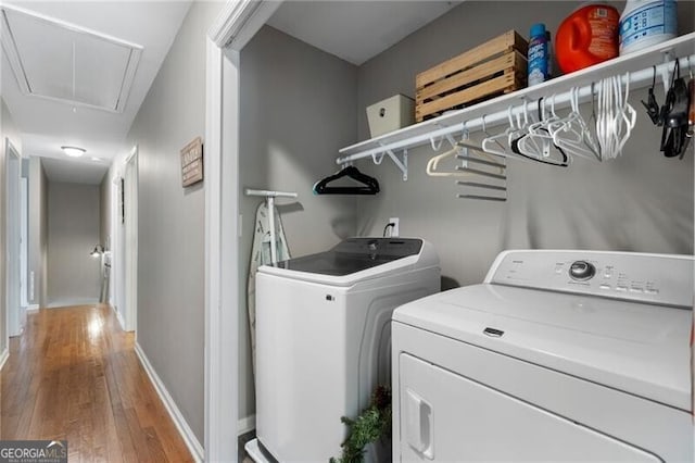 washroom featuring attic access, wood finished floors, laundry area, independent washer and dryer, and baseboards