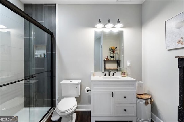 bathroom with a stall shower, vanity, toilet, and baseboards