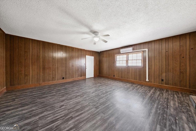 unfurnished room with a textured ceiling, dark wood-style flooring, a ceiling fan, baseboards, and an AC wall unit