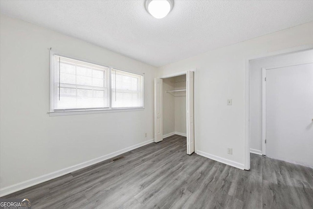 unfurnished bedroom featuring a closet, visible vents, baseboards, and wood finished floors