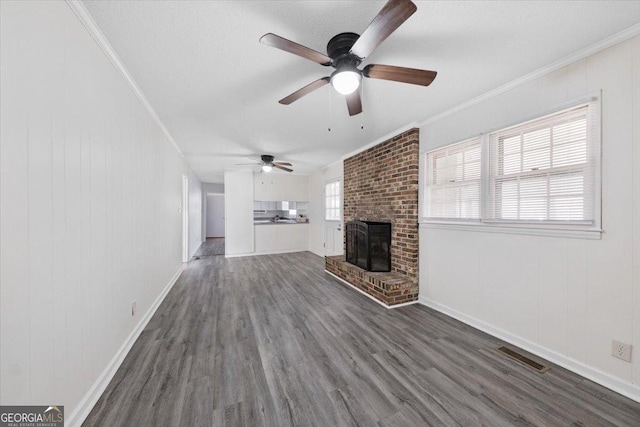 unfurnished living room with ornamental molding, visible vents, a fireplace, and wood finished floors