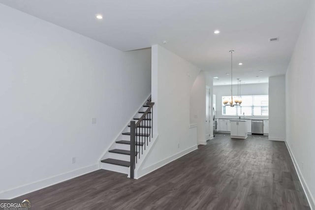 interior space featuring dark wood-type flooring, a notable chandelier, stairway, and baseboards