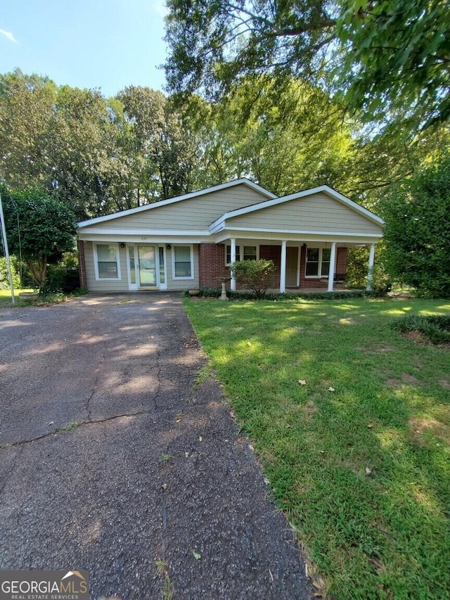 view of front of house featuring driveway, a porch, a front lawn, and brick siding