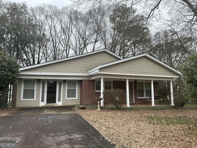 view of front of house featuring a porch, brick siding, and aphalt driveway