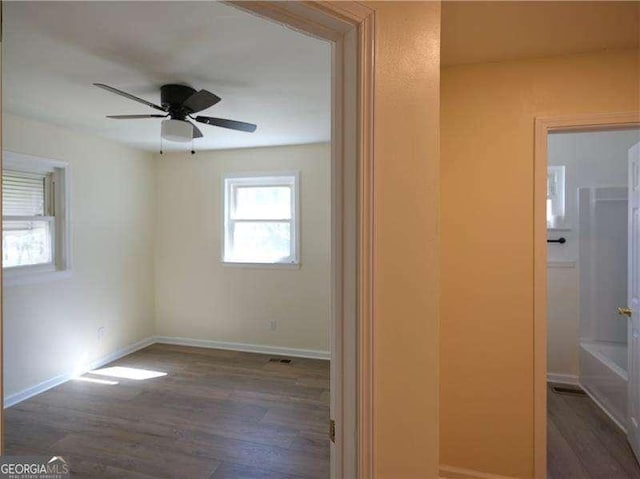 spare room featuring ceiling fan, baseboards, and wood finished floors