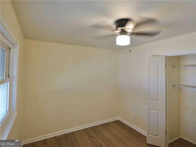 unfurnished bedroom with dark wood-style flooring, a closet, a ceiling fan, and baseboards