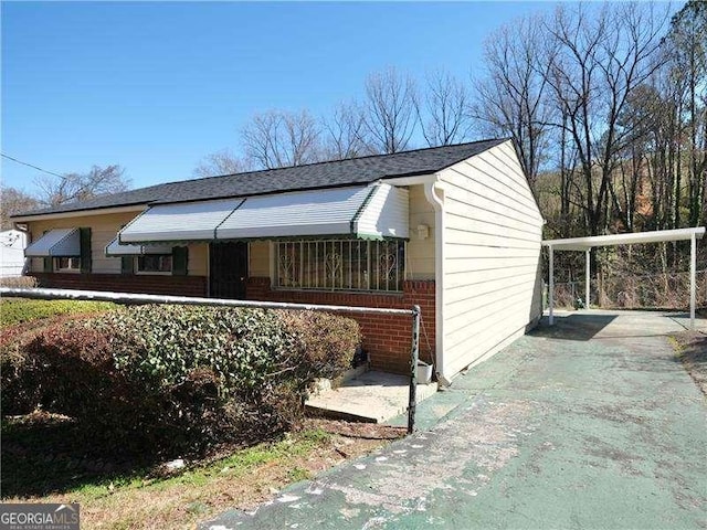 view of side of property with a carport, driveway, and brick siding