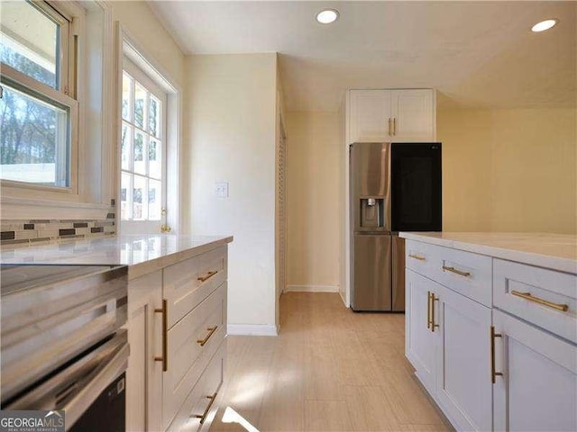 kitchen featuring stainless steel fridge, decorative backsplash, light countertops, white cabinetry, and recessed lighting