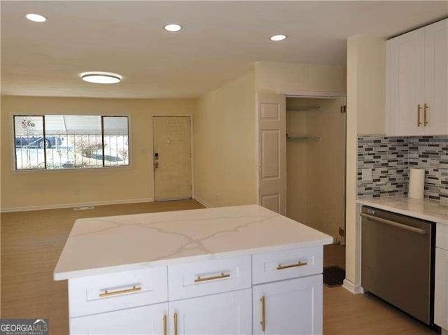 kitchen featuring tasteful backsplash, light wood-style flooring, stainless steel dishwasher, white cabinets, and a kitchen island