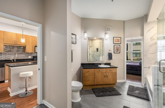 ensuite bathroom featuring decorative backsplash, ensuite bathroom, a stall shower, vanity, and baseboards