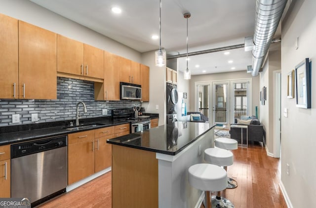 kitchen with a breakfast bar, backsplash, appliances with stainless steel finishes, light wood-style floors, and a sink