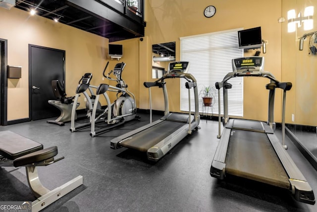 exercise room featuring baseboards and track lighting