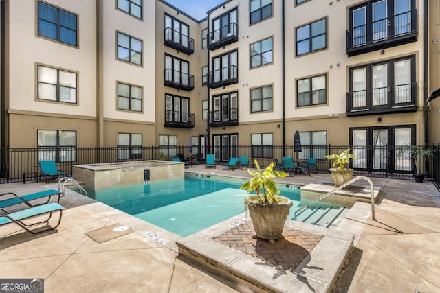 community pool featuring a community hot tub, a patio area, and fence