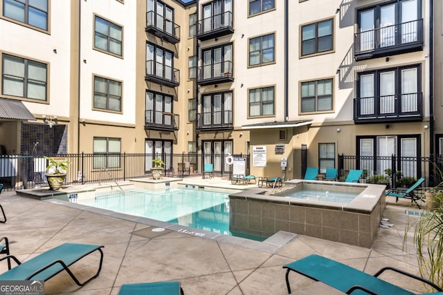 view of pool with a community hot tub and fence