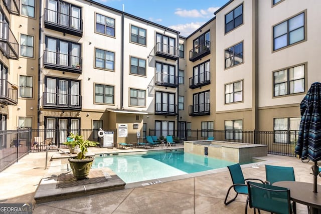 view of swimming pool featuring fence, a community hot tub, and a patio