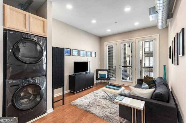 living area featuring stacked washing maching and dryer, baseboards, light wood finished floors, and recessed lighting