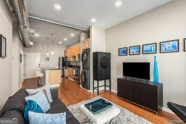 living room with stacked washer / dryer, wood finished floors, and recessed lighting