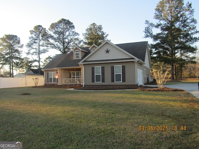 view of front of home featuring an attached garage, brick siding, fence, driveway, and a front lawn