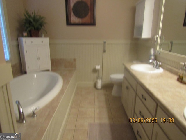 full bathroom with tile patterned flooring, wainscoting, vanity, and a bath