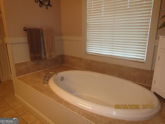 bathroom with tile patterned flooring, wainscoting, and a garden tub