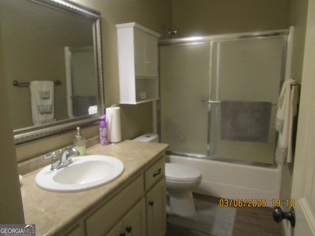 bathroom with toilet, combined bath / shower with glass door, and vanity