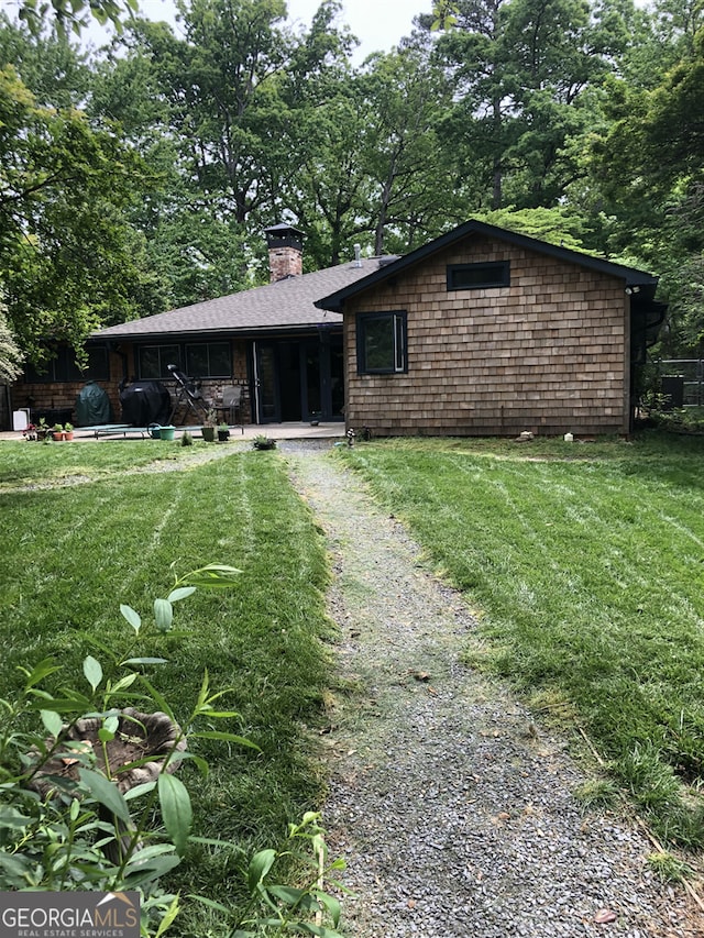 view of front facade with a front yard, driveway, and a chimney