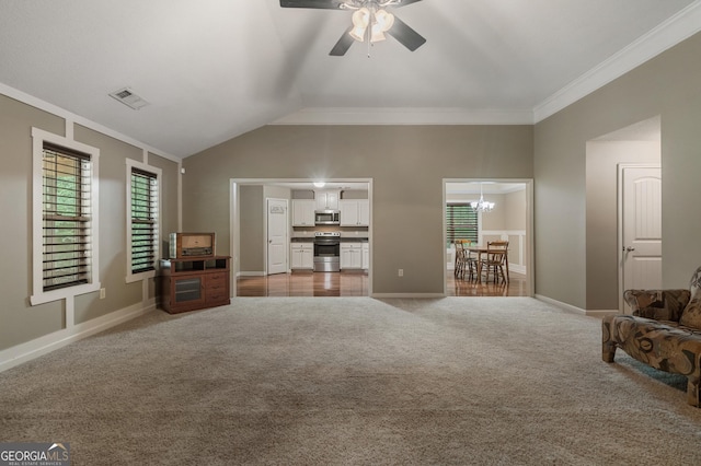 unfurnished living room featuring lofted ceiling, light carpet, ceiling fan with notable chandelier, baseboards, and ornamental molding