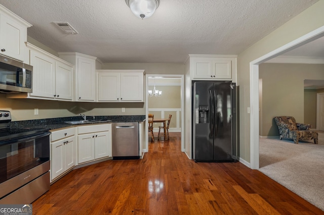 kitchen with stainless steel appliances, a sink, visible vents, white cabinets, and dark wood-style floors