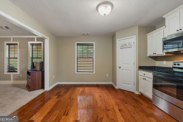 kitchen with appliances with stainless steel finishes, dark wood finished floors, visible vents, and white cabinetry