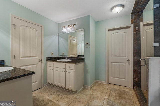 full bath with tiled shower, vanity, baseboards, and tile patterned floors